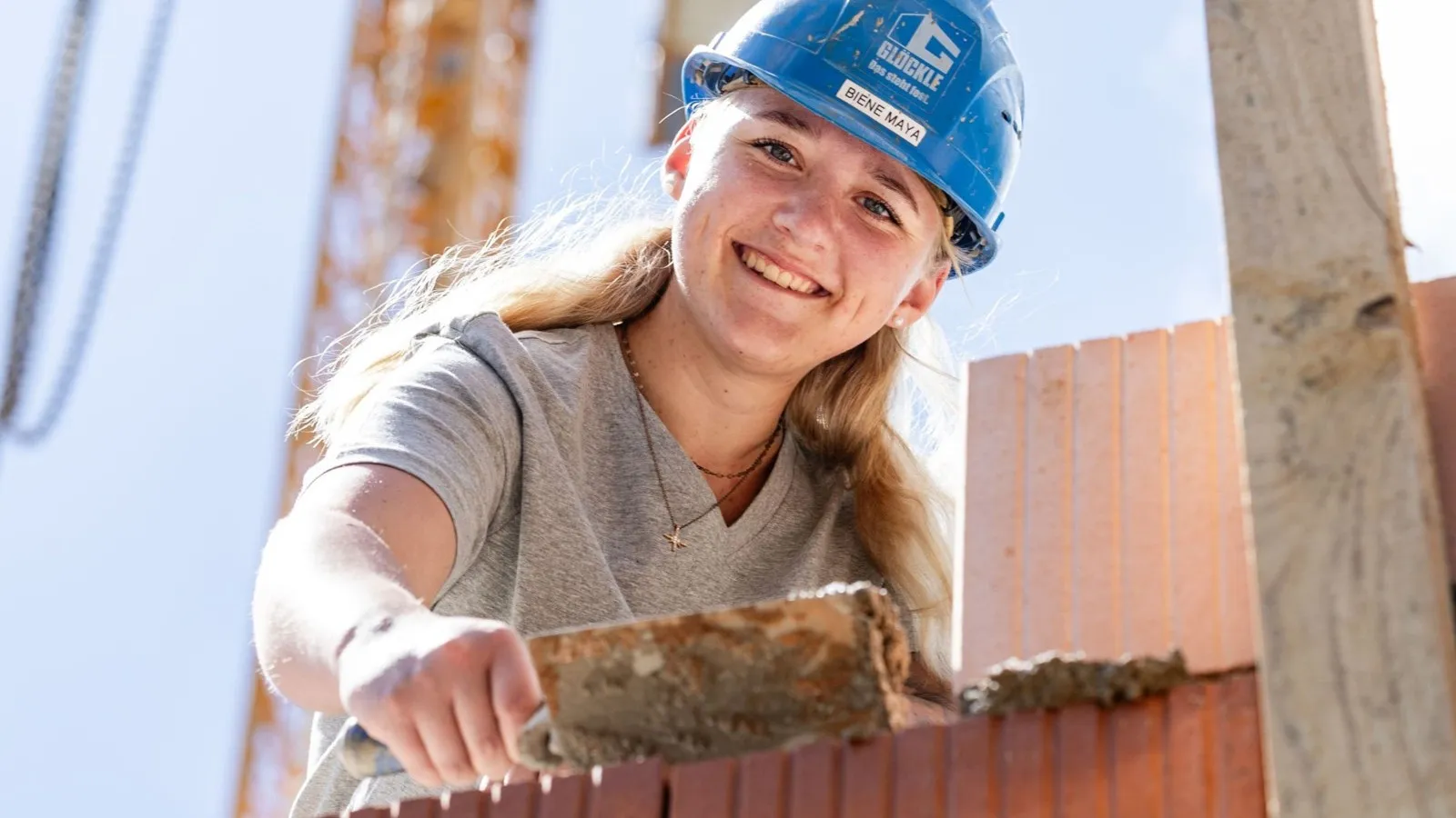 Maya Maxima Scheel mit einem blauen Schutzhelm bei ihrer Tätigkeit als Maurerin.